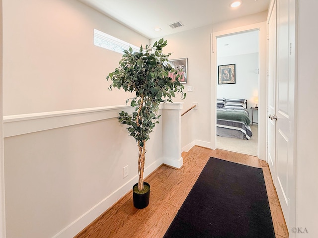 hallway featuring visible vents, baseboards, an upstairs landing, recessed lighting, and light wood-style floors