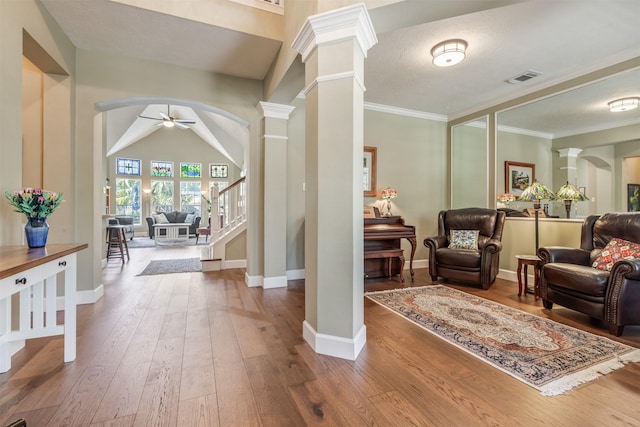 entrance foyer featuring decorative columns, arched walkways, wood-type flooring, and a ceiling fan