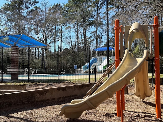 community playground featuring a community pool and fence