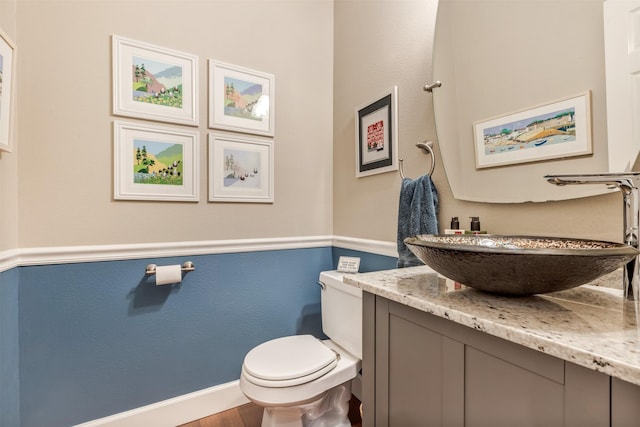 half bath with vanity, toilet, and baseboards