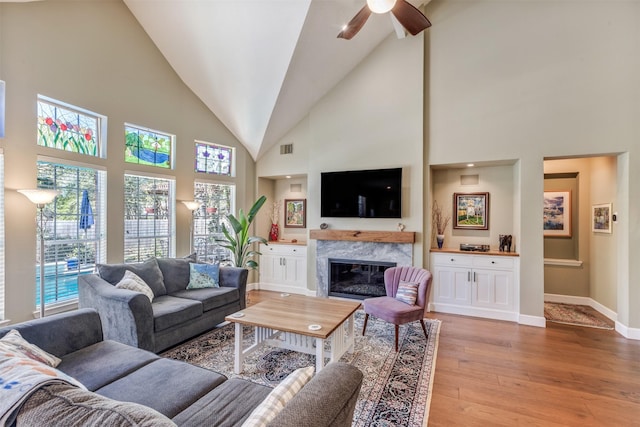 living area with a wealth of natural light, baseboards, light wood-style floors, and a fireplace