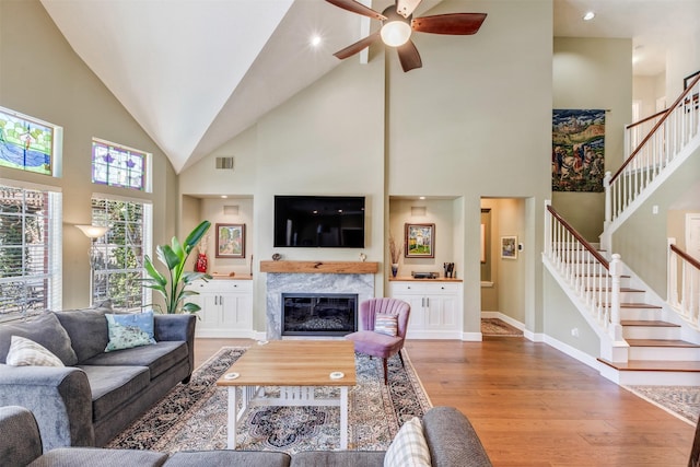 living room featuring light wood finished floors, stairway, visible vents, and a premium fireplace