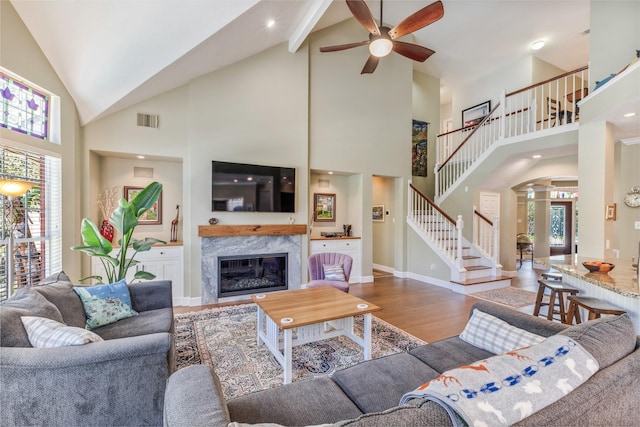 living room with visible vents, wood finished floors, a high end fireplace, stairway, and a healthy amount of sunlight