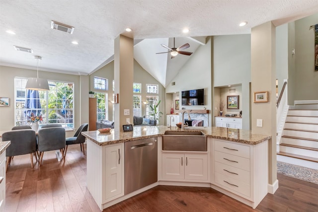 kitchen with visible vents, a sink, open floor plan, light stone countertops, and dishwasher