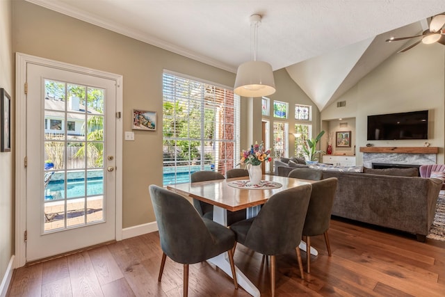 dining room with visible vents, baseboards, lofted ceiling, a fireplace, and hardwood / wood-style flooring