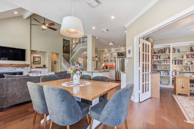 dining area featuring visible vents, hardwood / wood-style flooring, crown molding, a fireplace, and stairs