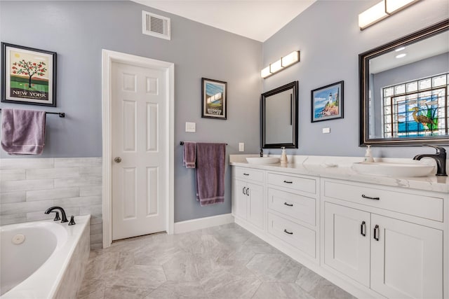 full bath featuring a bath, visible vents, double vanity, and a sink