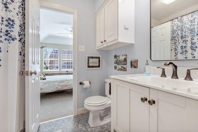 ensuite bathroom featuring toilet, lofted ceiling, tile patterned floors, vanity, and a ceiling fan