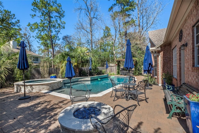 view of swimming pool with a patio, a fire pit, a pool with connected hot tub, and fence