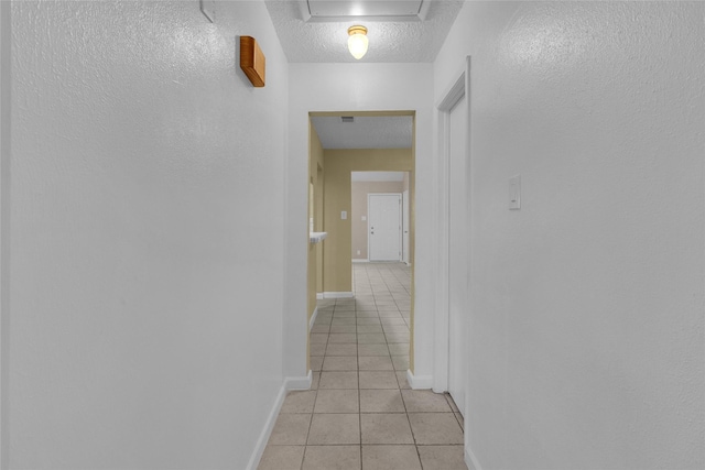 hall featuring light tile patterned floors, visible vents, baseboards, and a textured ceiling