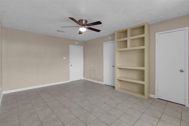 unfurnished bedroom with visible vents, a ceiling fan, a textured ceiling, light tile patterned floors, and baseboards