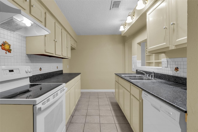 kitchen with white appliances, visible vents, a sink, under cabinet range hood, and dark countertops