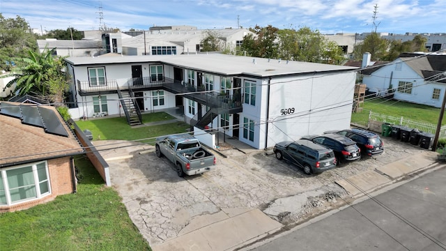 view of front of property featuring fence, stairway, a residential view, a front yard, and a balcony