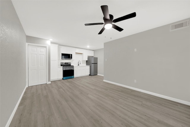 unfurnished living room with a sink, light wood-style floors, visible vents, and baseboards