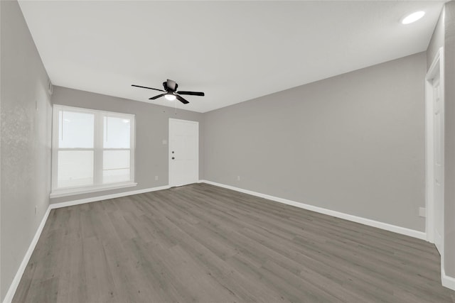 spare room with a ceiling fan, wood finished floors, and baseboards