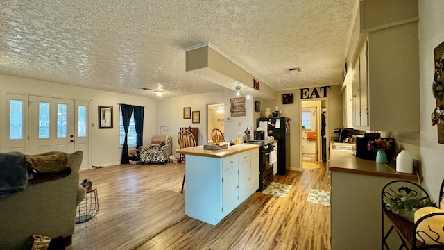 kitchen featuring visible vents, light wood-style floors, a peninsula, and open floor plan