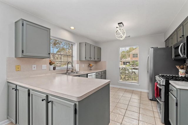 kitchen with a sink, stainless steel appliances, plenty of natural light, and gray cabinetry