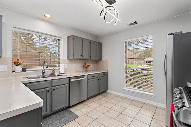 kitchen featuring visible vents, gray cabinetry, a sink, stainless steel appliances, and light countertops