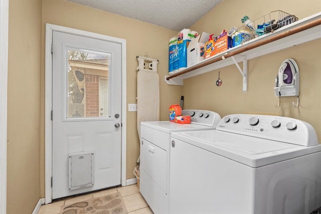 laundry room featuring baseboards, laundry area, light tile patterned flooring, a textured ceiling, and washer and dryer