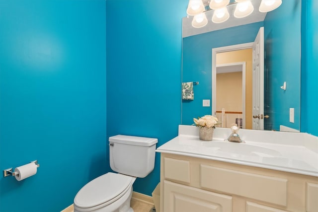 bathroom with baseboards, toilet, and vanity