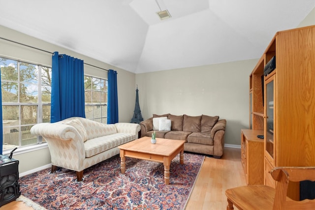 living room with lofted ceiling, light wood-style floors, visible vents, and baseboards