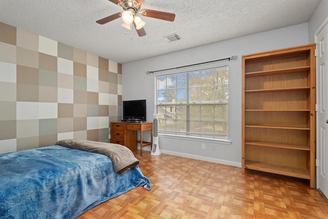 bedroom with baseboards, visible vents, wallpapered walls, a textured ceiling, and an accent wall