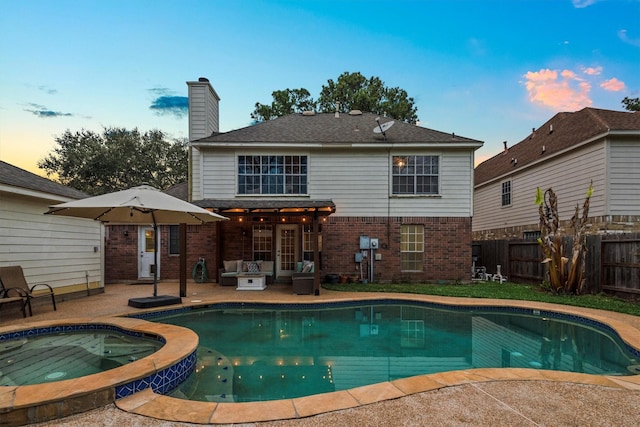 pool at dusk featuring a patio area, fence, and a pool with connected hot tub