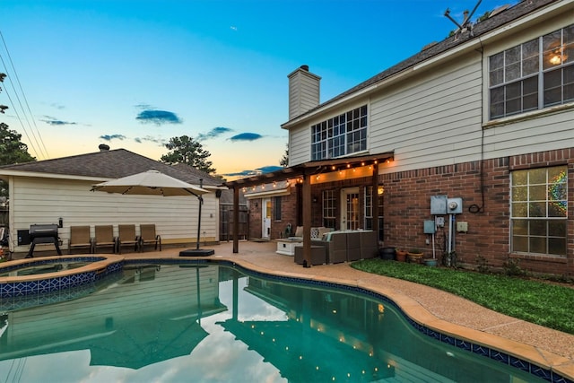 pool at dusk featuring a patio area and a pool with connected hot tub