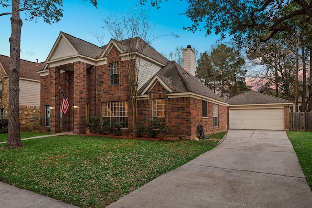 traditional-style home featuring brick siding, a front yard, a chimney, a garage, and an outbuilding