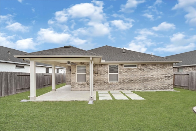 rear view of property with a lawn, a fenced backyard, a shingled roof, brick siding, and a patio area