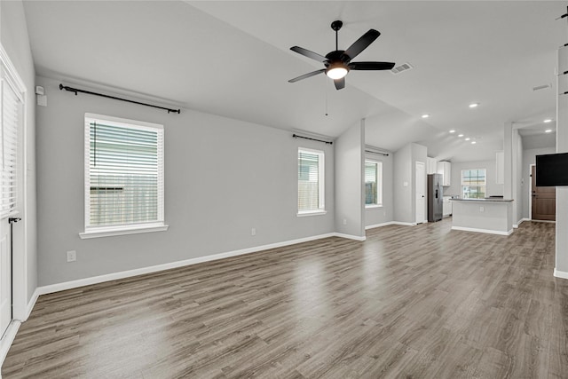 unfurnished living room featuring baseboards, visible vents, ceiling fan, vaulted ceiling, and light wood-type flooring