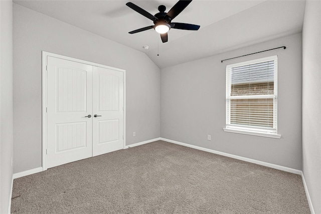 unfurnished bedroom with a closet, carpet flooring, baseboards, and lofted ceiling