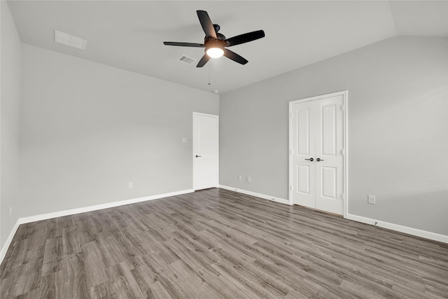 unfurnished bedroom with visible vents, baseboards, wood finished floors, and vaulted ceiling