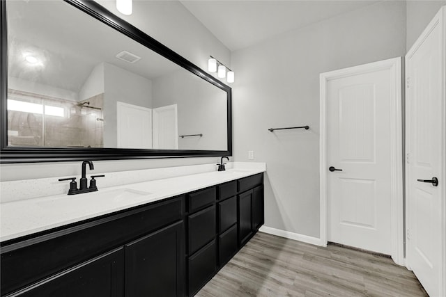 bathroom featuring a sink, visible vents, tiled shower, and wood finished floors