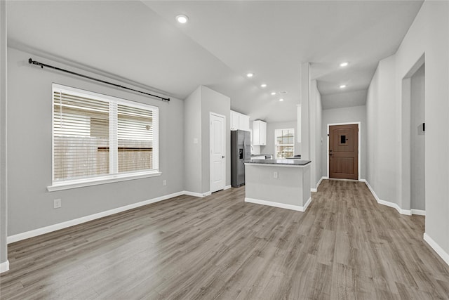 unfurnished living room with recessed lighting, light wood-style flooring, baseboards, and vaulted ceiling