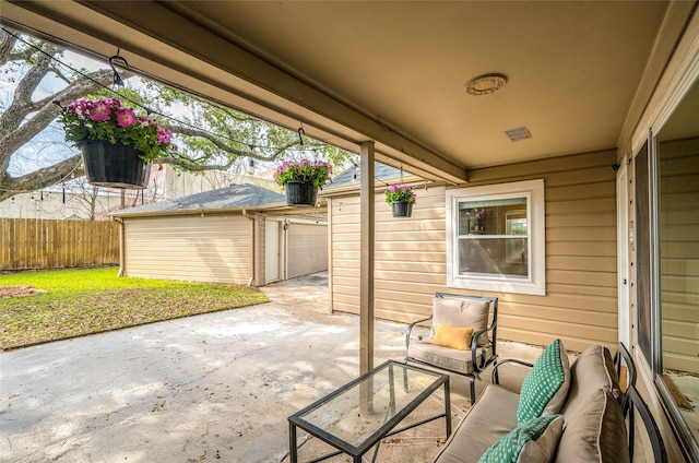 view of patio with an outbuilding, concrete driveway, fence, and a garage