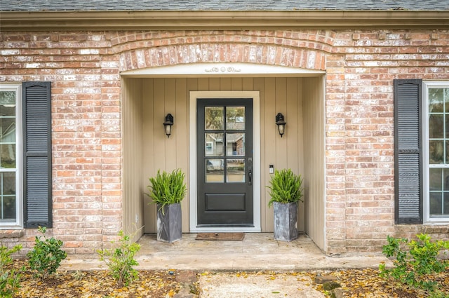 entrance to property featuring board and batten siding, brick siding, and roof with shingles