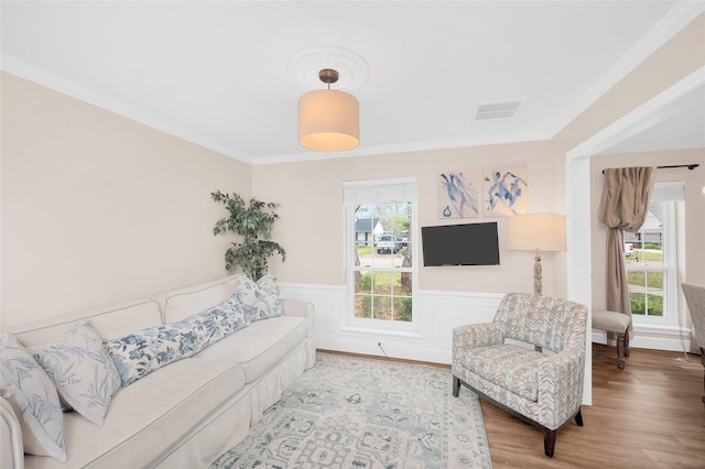 living room with visible vents, wood finished floors, wainscoting, and crown molding