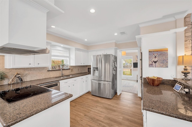 kitchen featuring stainless steel fridge with ice dispenser, a sink, crown molding, wall chimney exhaust hood, and black electric cooktop