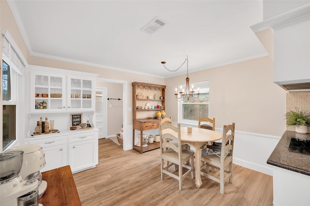 dining area with visible vents, an inviting chandelier, ornamental molding, and light wood finished floors