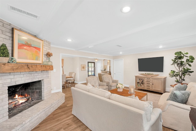 living area with light wood-type flooring, visible vents, a fireplace, crown molding, and baseboards