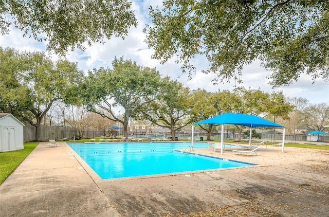 pool featuring an outbuilding, a storage unit, and fence