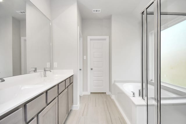 bathroom featuring visible vents, a garden tub, and a sink