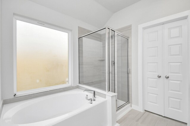 full bathroom with a bath, a shower stall, and vaulted ceiling