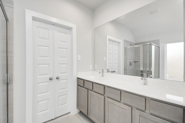 full bath with visible vents, a shower stall, a sink, and double vanity