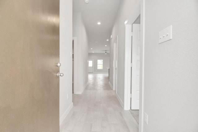 hall with recessed lighting and baseboards