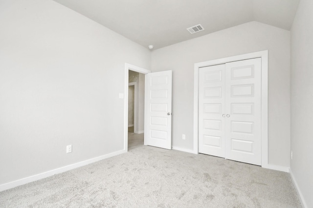 unfurnished bedroom featuring visible vents, baseboards, carpet, and vaulted ceiling