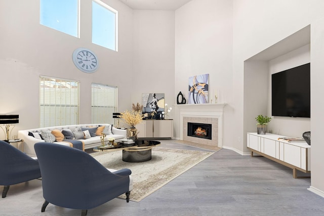 living room with baseboards, a high ceiling, wood finished floors, and a tile fireplace