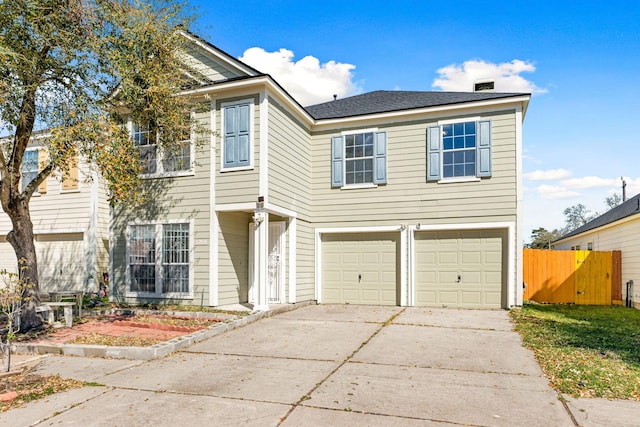 view of front of home with an attached garage, concrete driveway, and fence