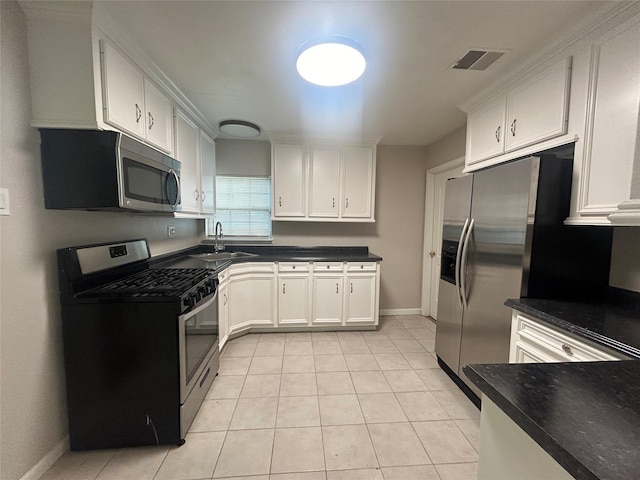 kitchen with visible vents, a sink, appliances with stainless steel finishes, white cabinetry, and dark countertops